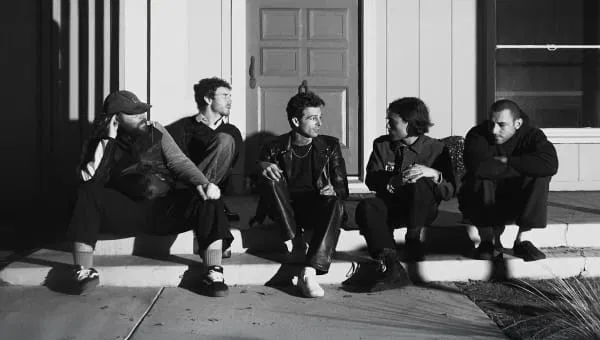 De band The Neighbourhood in zwart-wit, zittend voor een deur